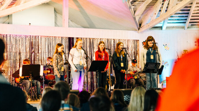 lapset esiintymässä lavalla. Kuvan etuosassa näkyy yleisöä.