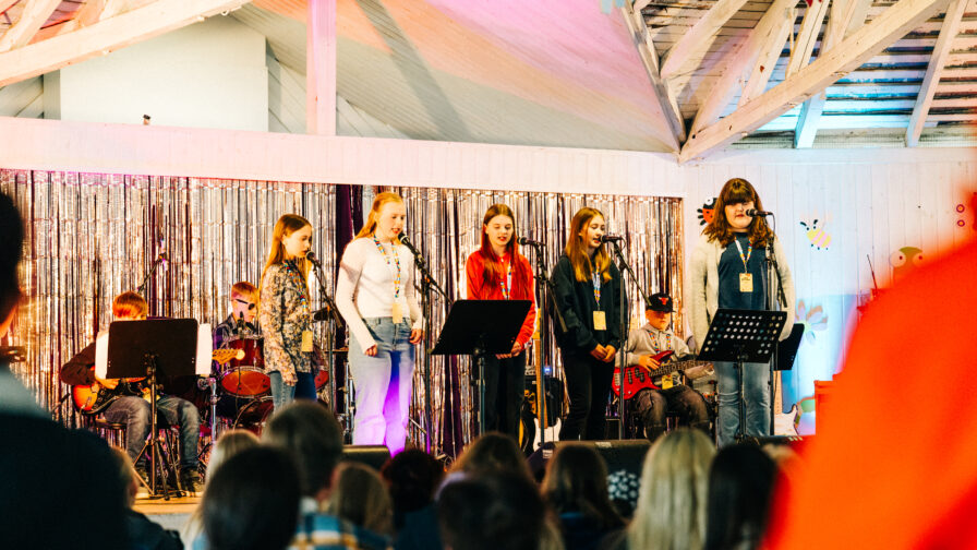 lapset esiintymässä lavalla. Kuvan etuosassa näkyy yleisöä.